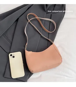 Pink crescent hobo bag size compared to a smartphone on grey blazer background