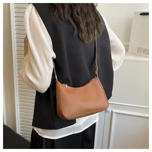 Lifestyle shot of a caramel brown leather crescent shoulder bag worn as an underarm bag