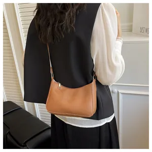 Detailed view of caramel crescent shoulder bag with white contrast stitching and silver zipper