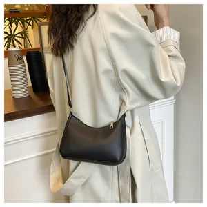 Detail showing sleek black PU leather shoulder bag with elegant gold hardware on a model