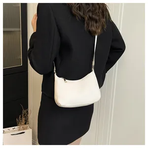 Rear view of a model wearing a creamy white half-moon shoulder bag with gold zipper detail