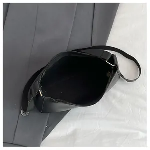 Close-up of black glossy synthetic leather handbag showing smooth zipper and interior lining