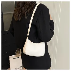 Detailed view of a white minimalist hobo bag styled with a high-contrast black outfit