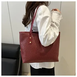 Detail of burgundy woven tote bag showing fine texture and gold rivet shoulder strap