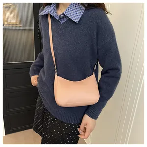 Close-up of a minimalist light pink crossbody bag with adjustable strap on a female model