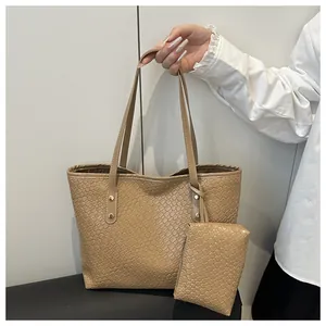 Detail of beige woven tote bag with matching small pouch and metallic gold rivet accents