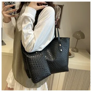 Detail of black woven leather tote bag with matching pouch and metal rivet strap