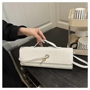Détail de la texture croco blanc et boucle métallique hexagonale dorée du sac à bandoulière