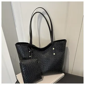 Detail of black woven leather tote and matching pouch set with golden metal studs