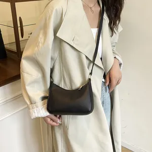 Minimalist black crescent crossbody bag with gold hardware shown on a model