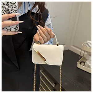 Detail of cream white patent leather mini bag featuring golden metal bar and chain strap