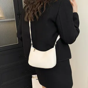 Minimalist beige crescent shoulder bag with gold zipper and matte leather finish