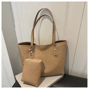 Detail of beige woven tote bag set showing leather texture and gold-tone hardware