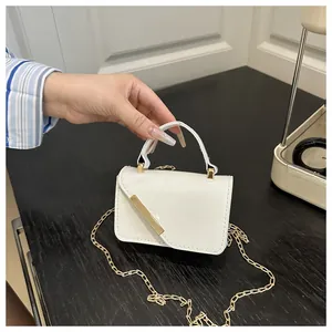 Detailed macro view of white mini patent leather handbag with gold chain strap