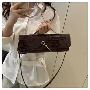 Détails d'un sac à main marron foncé à texture crocodile et fermoir métallique doré