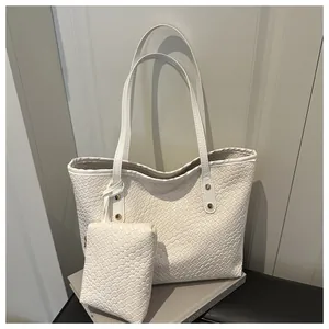 Detail of white woven leather tote bag with gold hardware and matching small pouch