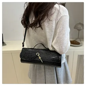 Détail du sac à bandoulière noir motif crocodile avec fermoir métallique hexagonal doré