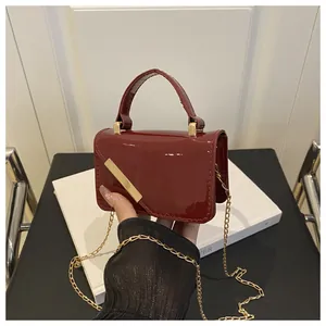 Detail of wine red glossy mini crossbody bag with gold metal trim and chain strap