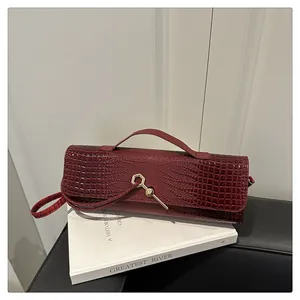 Détail du sac baguette bordeaux avec motif crocodile et fermoir en métal géométrique