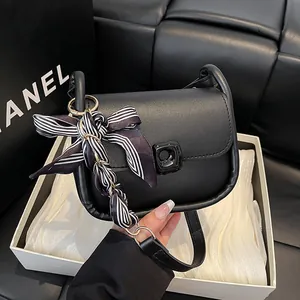 Minimalist black leather shoulder bag with striped silk scarf and metal turn-lock