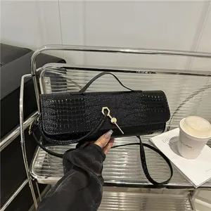 Sac baguette noir à texture crocodile avec fermoir doré et bandoulière chic