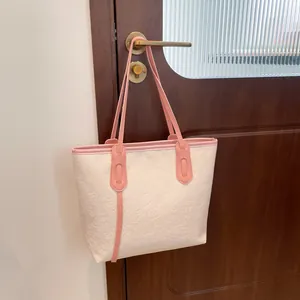 Grand sac cabas crème avec bordure rose et motifs cœurs suspendu à une porte