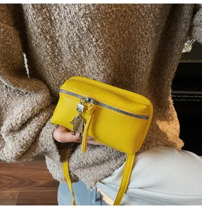 Close-up of bright yellow small square crossbody bag featuring a silver robot charm