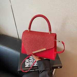 Elegant red handbag with shiny fabric details and golden metal trim on a stylish couch