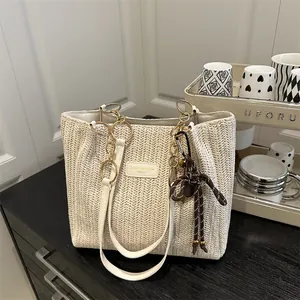 Elegante borsa tote in paglia beige con trama a V e nappine in corda marrone decorative