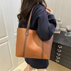 Large caramel and brown contrast stitch tote bag worn over the shoulder for daily commute