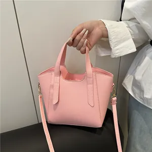 Pink lychee texture bucket bag with dual handles and detachable strap shown in hand