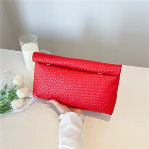 Minimalist red woven leather envelope clutch bag held in hand for a stylish look