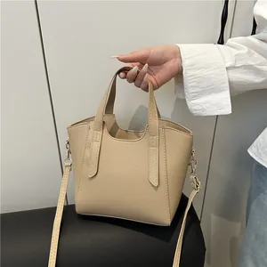 Beige lychee textured bucket bag with top handles and a detachable shoulder strap