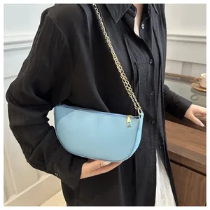 Detail einer hellblauen Leder-Halbmondtasche mit eleganter goldener Ketten-Schulterkette