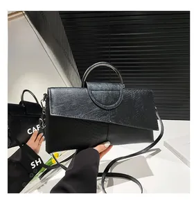 Dettaglio pochette nera effetto coccodrillo con manico ad anello in metallo argentato
