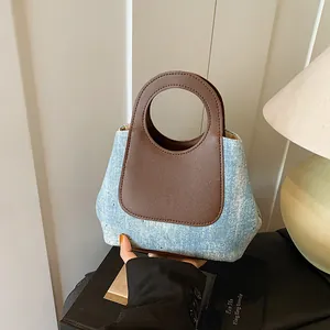 Contrast color bucket bag with denim fabric, rivets and circular leather handle for women