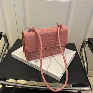 Pink crocodile pattern shoulder bag with a square metal buckle on a minimalist background