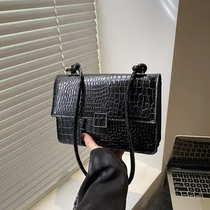Elegant black crocodile embossed crossbody bag with silver square lock on a sunlit window