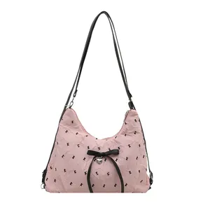 Pink ruched shoulder bag with black bows, heart pendant, and double straps design