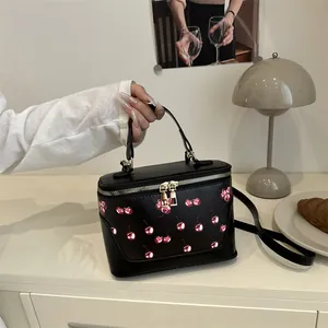 Retro black box handbag with cherry print and golden zippers in a modern lifestyle setting