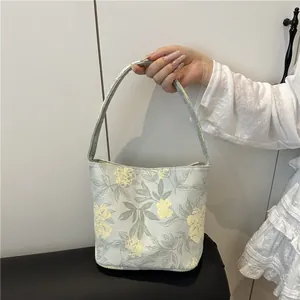Sac à main gris élégant avec broderies florales jaunes et design de seau minimaliste