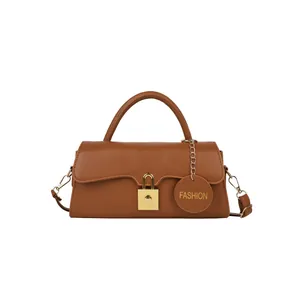 Sac bandoulière marron rétro avec serrure dorée et breloque mode sur fond blanc