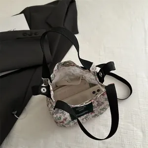 Sac seau floral vintage avec poignée en sangle noire et fermeture aimantée sur fond blanc