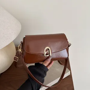 Minimalist deep brown crossbody bag with a glossy faux leather finish and gold buckle