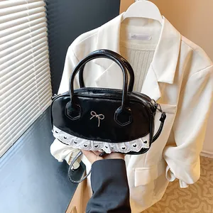 Chic black patent leather Boston bag with white lace trim and gold bow detail