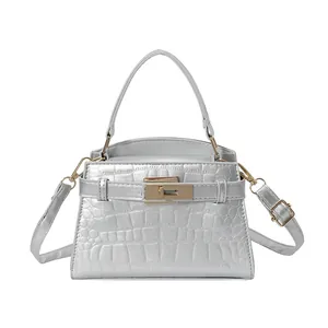 Silver metallic trapezoid handbag with crocodile texture and gold lock on white background