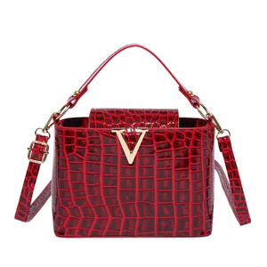 Red crocodile pattern bucket bag with golden V-logo and glossy patent leather finish