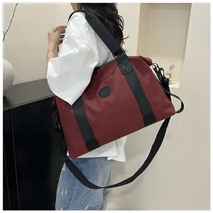 Close-up of burgundy large capacity travel bag with black straps and brand logo