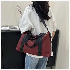 Detail view of burgundy large yoga travel bag with black straps on a model's shoulder
