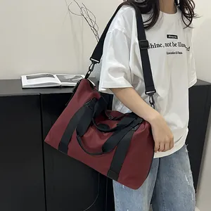 Deep red large capacity travel fitness bag with shoulder strap worn by a model